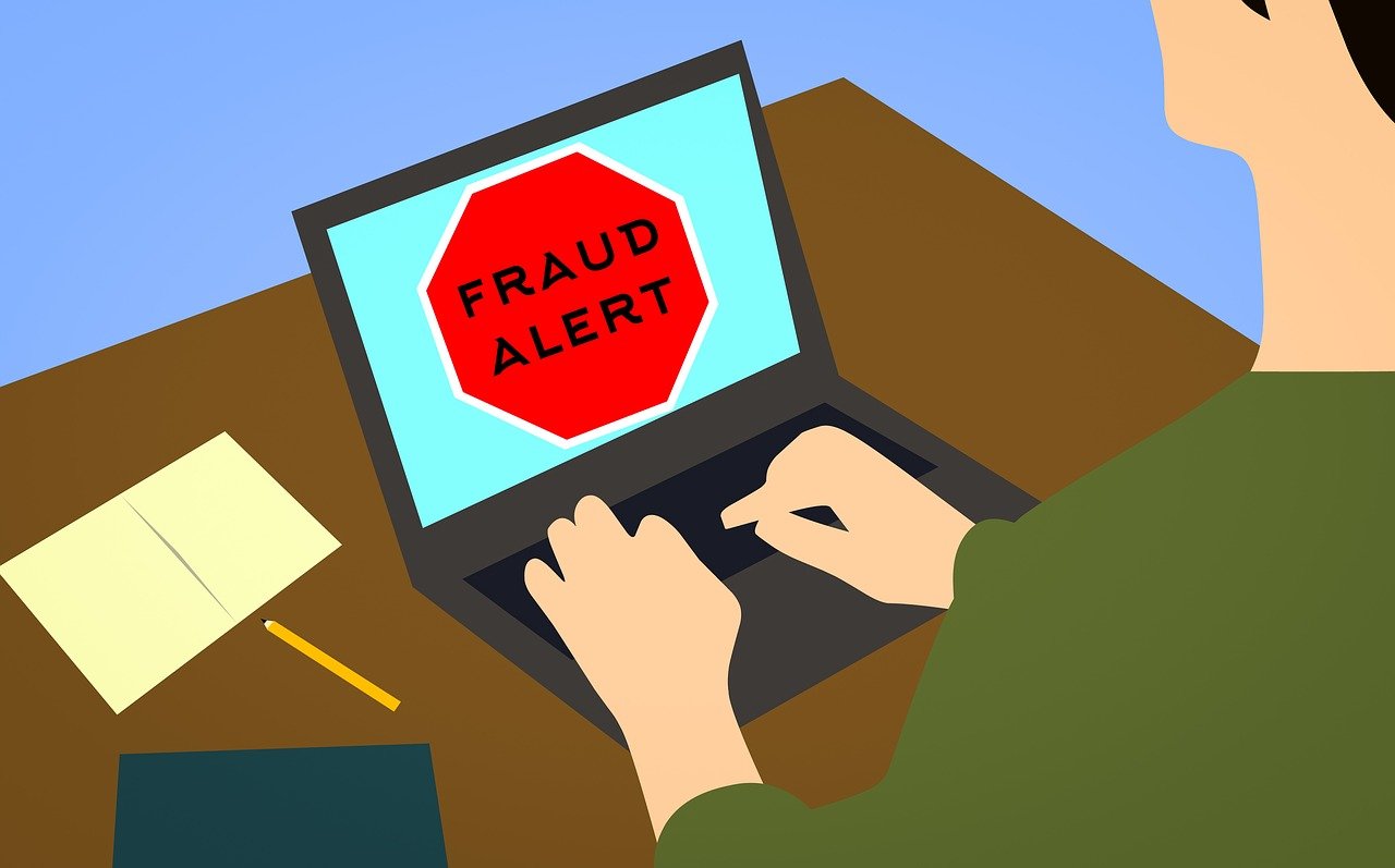 Ilustrace: muž u notebooku s červeným varováním „Fraud alert“
